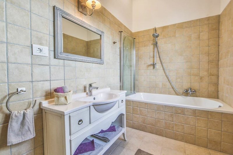 Stylish bathroom with a purple cabinet, mirror, and modern fixtures.