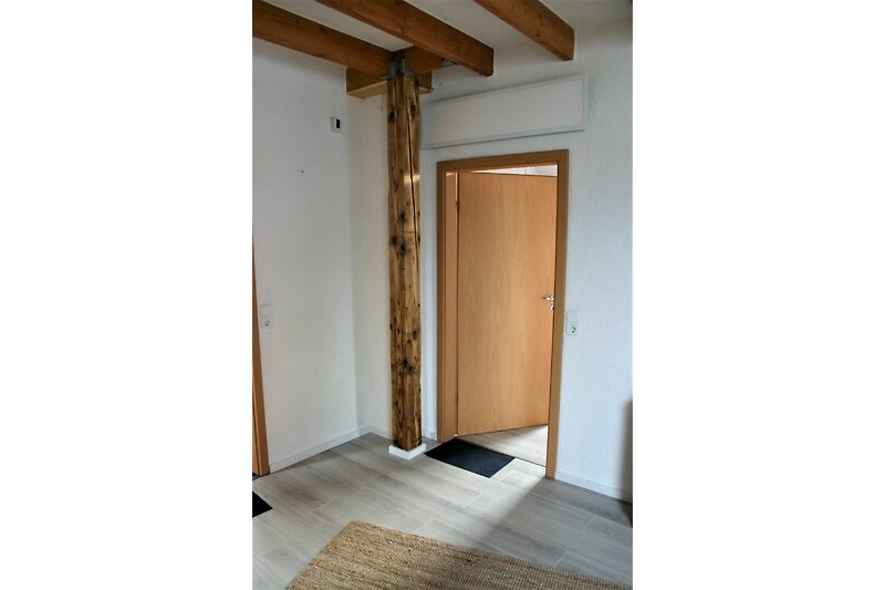 Holzhaus mit Holzboden, Holzwand und Holztür in schattigem Bereich.