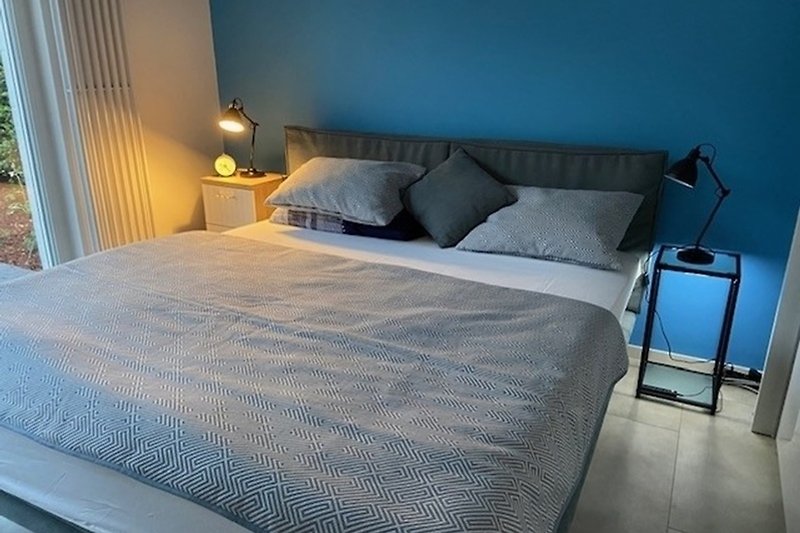 Blaues Schlafzimmer mit Boxspringbett 1,80 x 2,00 m, Kleiderschrank, Tisch und Stuhl, Terrasse