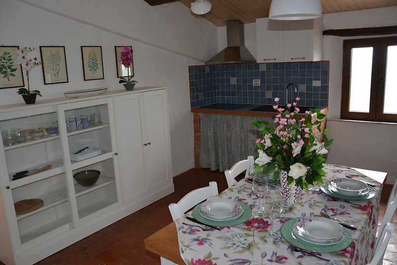Una tavola ben apparecchiata con fiori freschi e una vista sulla cucina.