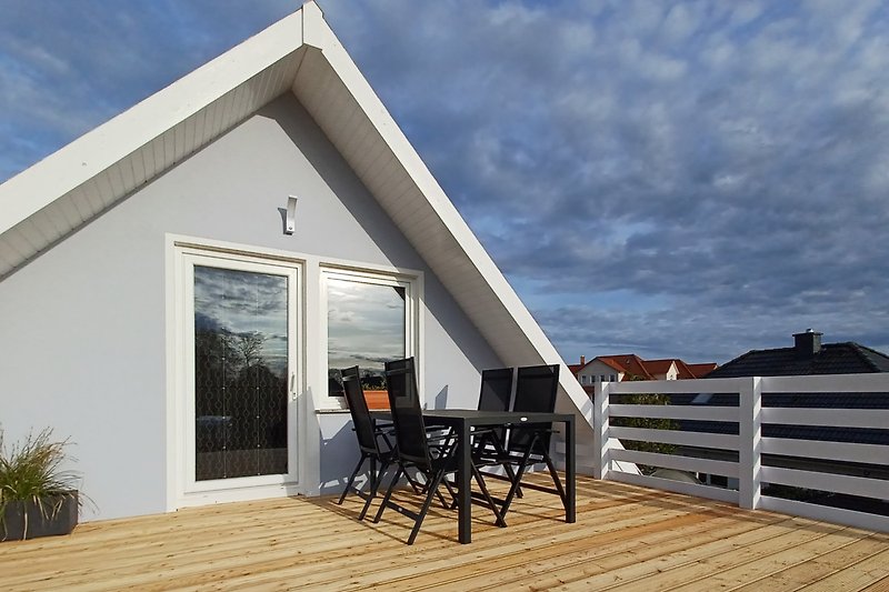 Charmante Terrasse mit Holzdeck, Blumen und Blick auf den Ozean.