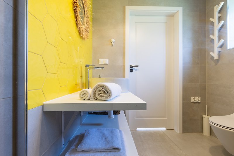 Elegancka łazienka z żółtym wyposażeniem i nowoczesnymi dodatkami.