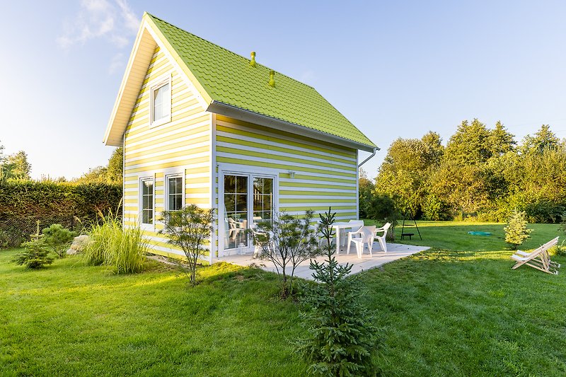 Piękny dom na wsi z zadbanym ogrodem i dużymi oknami.