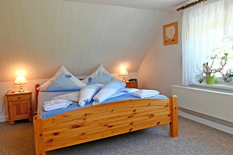 Gemütliches Schlafzimmer mit Holzbett, Lampen und gemütlicher Einrichtung.