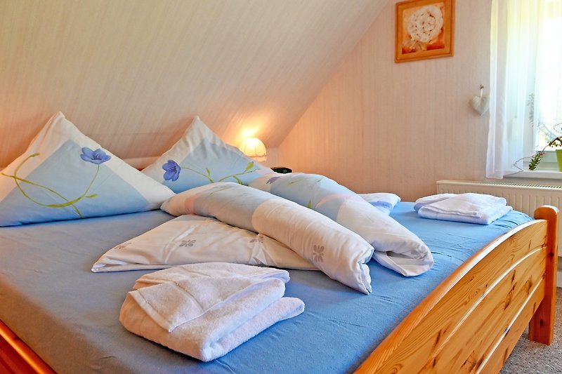 Gemütliches Schlafzimmer mit Holzbett, orangenen Kissen und Textilien.