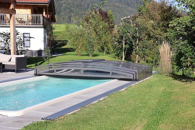 Ein idyllischer Garten mit Pool und Außenmöbeln.