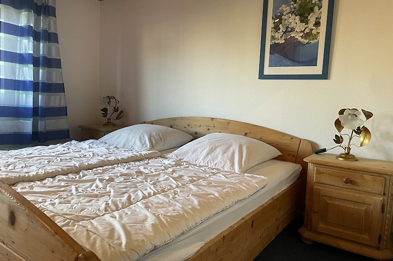 Gemütliches Schlafzimmer mit blauem Bett, Holzmöbeln und stilvollem Interieur.