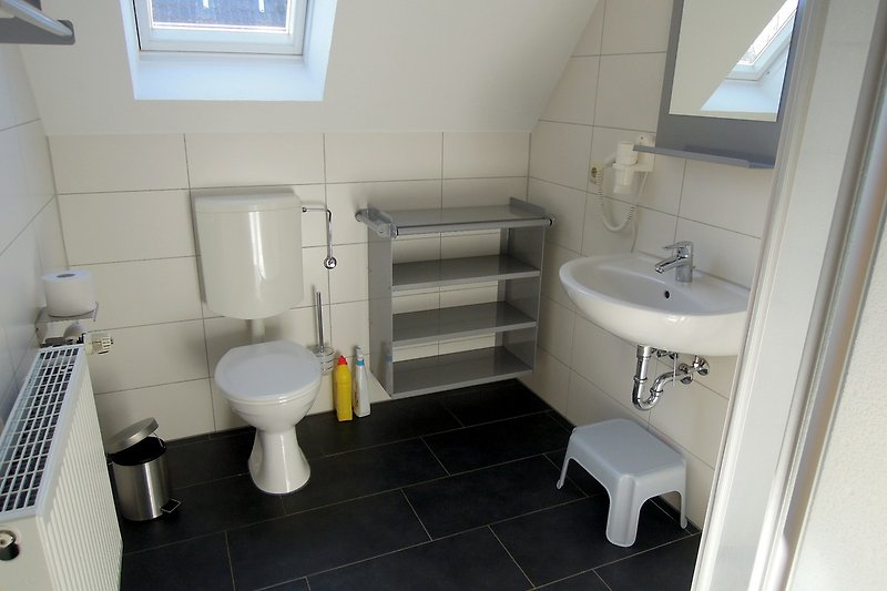 Gemütliches Badezimmer mit Akzenten, Spiegel und Toilette.
