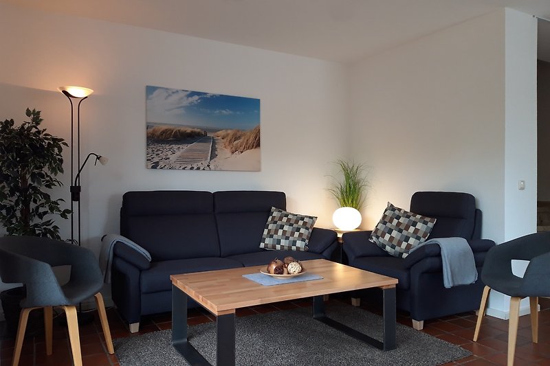 Gemütliches Wohnzimmer mit bequemer Couch, Tisch und Pflanzen.