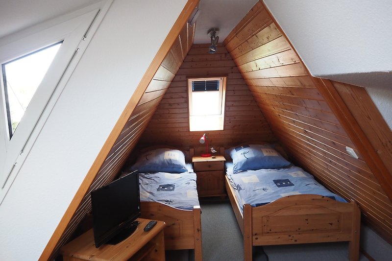 Dachschlafzimmer mit gemütlichem Bett und Holzdecke.
