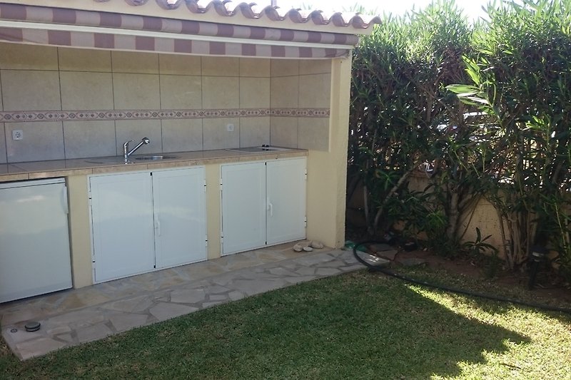 Außenküche im privaten Garten mit Kühlschrank, Spüle und Bratplatte
