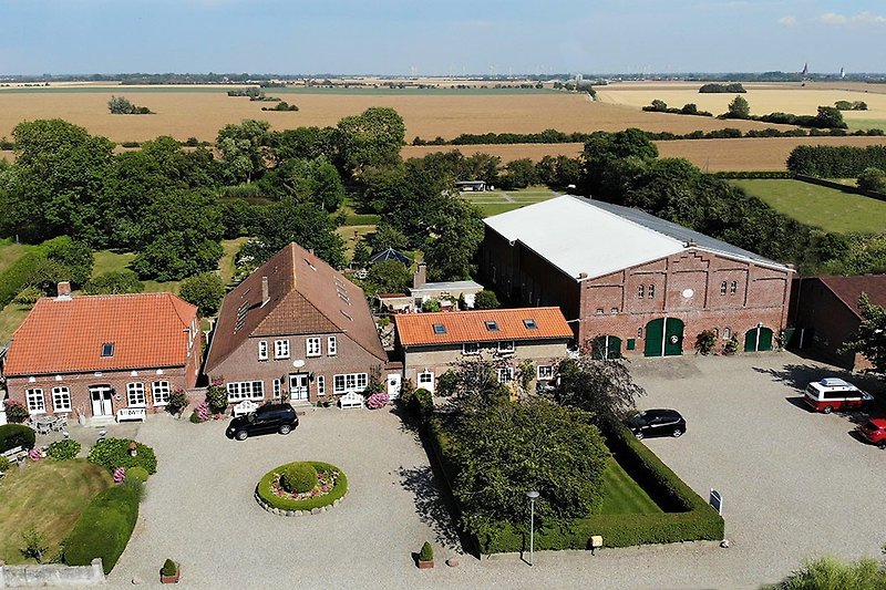 Ländliche Aussicht mit Haus, Garten und weitem Himmel.