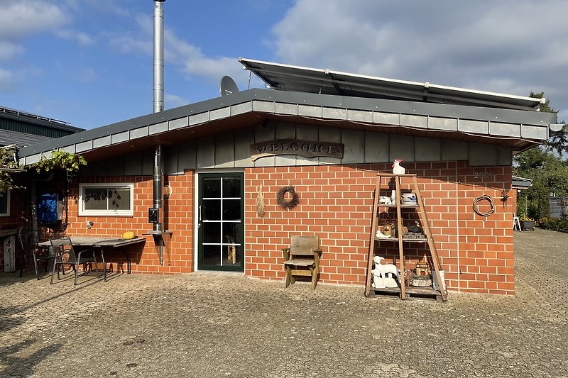 Gemütliches Holzhaus mit Fenstern, Dach und umgeben von Bäumen.