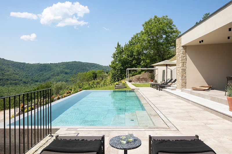 Entspannen Sie sich am Pool und genießen Sie die Aussicht auf das Haus und die Landschaft.