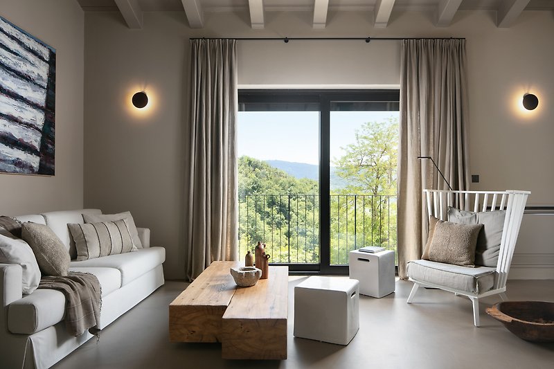 Relaxen Sie auf dem bequemen Sofa und genießen Sie den Blick aus dem Fenster auf die grüne Landschaft.