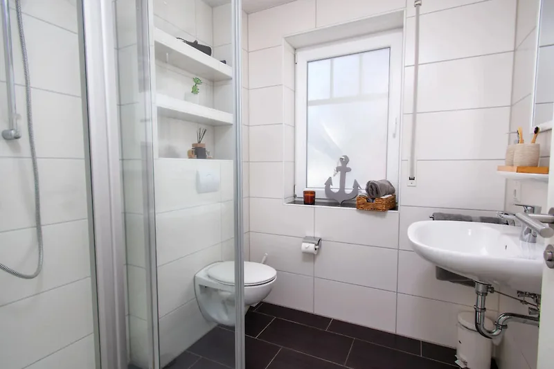 Geräumiges Bad mit Glasdusche, Bidet, Spiegel und Pflanzenakzent.