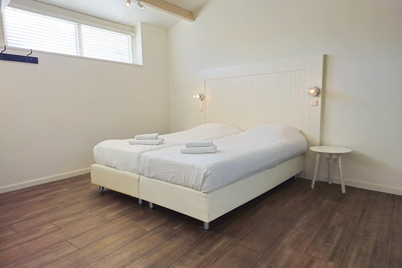 Gemütliches Schlafzimmer mit stilvollem Holzboden und gemütlichem Bett.