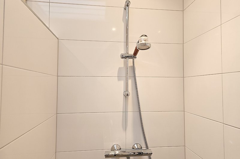 Modernes Badezimmer mit Dusche, Fliesen und Metallarmaturen.
