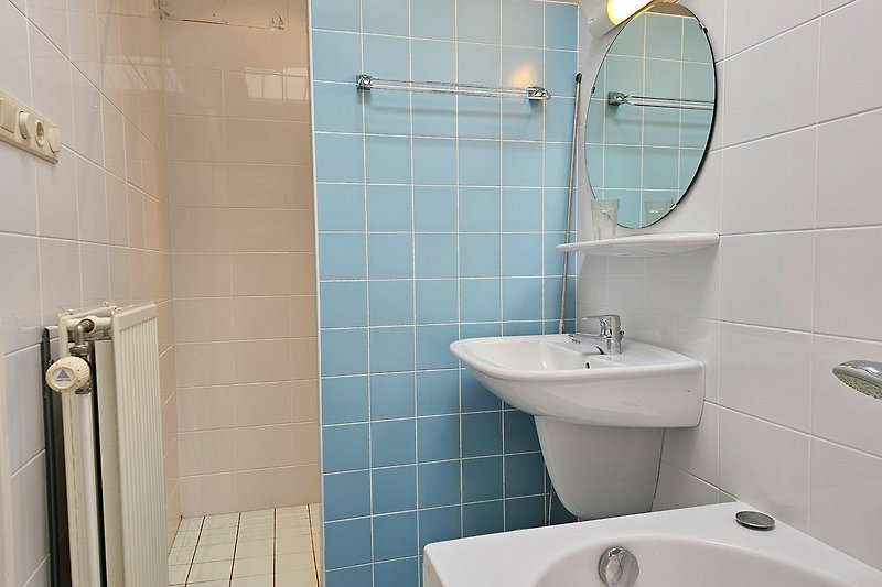 Modernes Badezimmer mit lila, schwarzen und blauen Fliesen, Spiegel und Armatur.