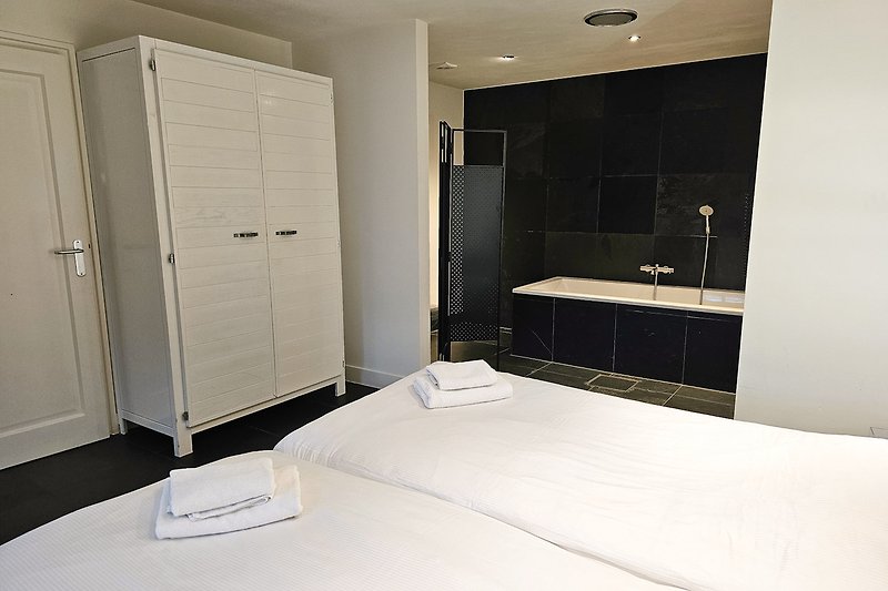 Stilvolles Schlafzimmer mit Badezimmer mit moderner Badewanne ensuite.