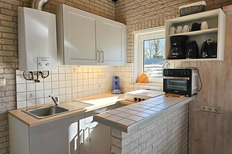 Moderne Küche mit Gasofen, Spüle, Schränken und Arbeitsplatte.