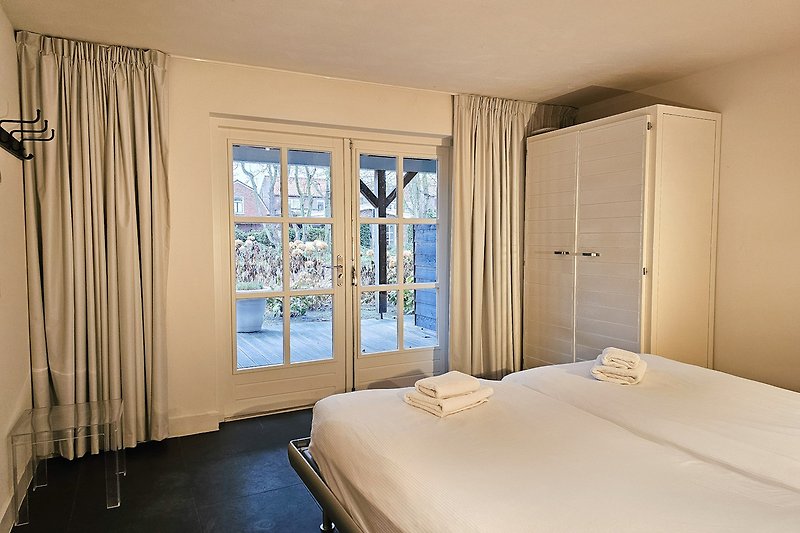 Stilvolles Schlafzimmer mit gemütlichem Bett und Flügeltüren nach die Terrasse.