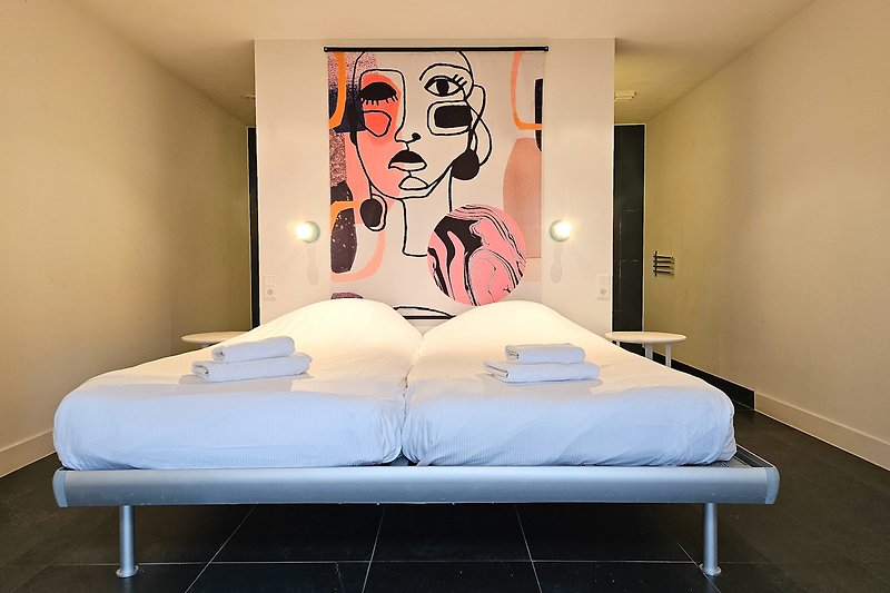Stilvolles Schlafzimmer mit gemütlichem Bett und moderner Kunst.