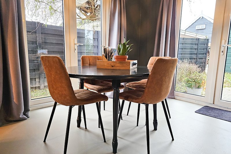 Gemütliche Einrichtung mit Tisch, Stühlen und Pflanzen.