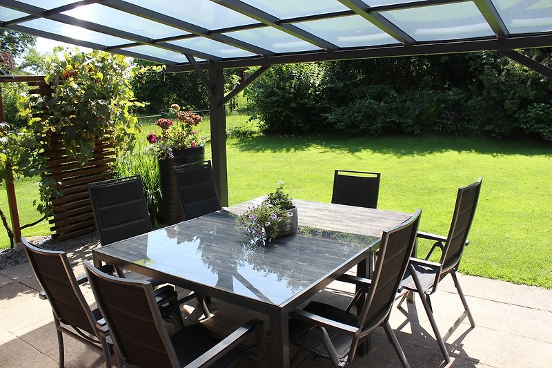 Gemütliche Terrasse mit Tisch, Stühlen und Pflanzen.