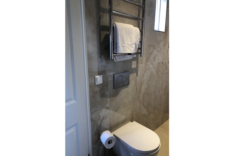 Moderne badkamer met glazen douche en strakke tegels.