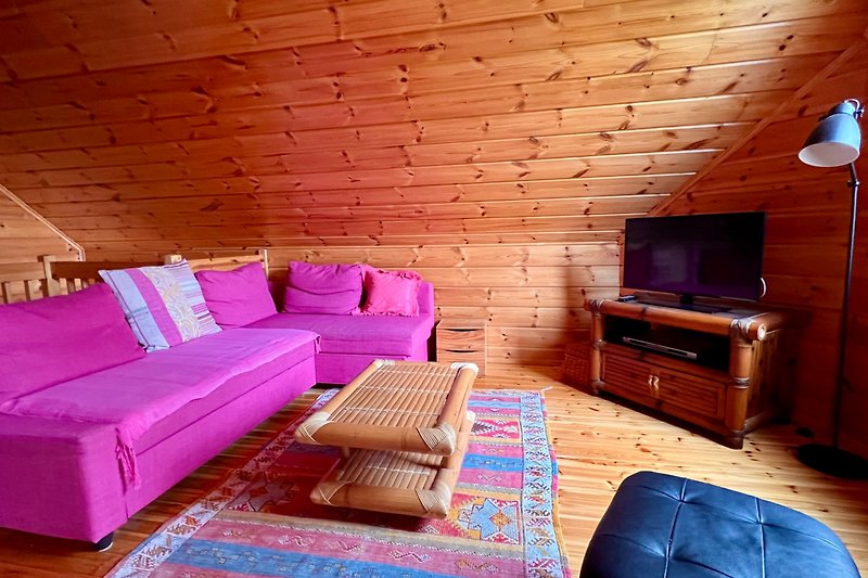 Wohnzimmer mit violettem Sofa, Holzmöbeln und Lampen. Gemütliche Einrichtung.
