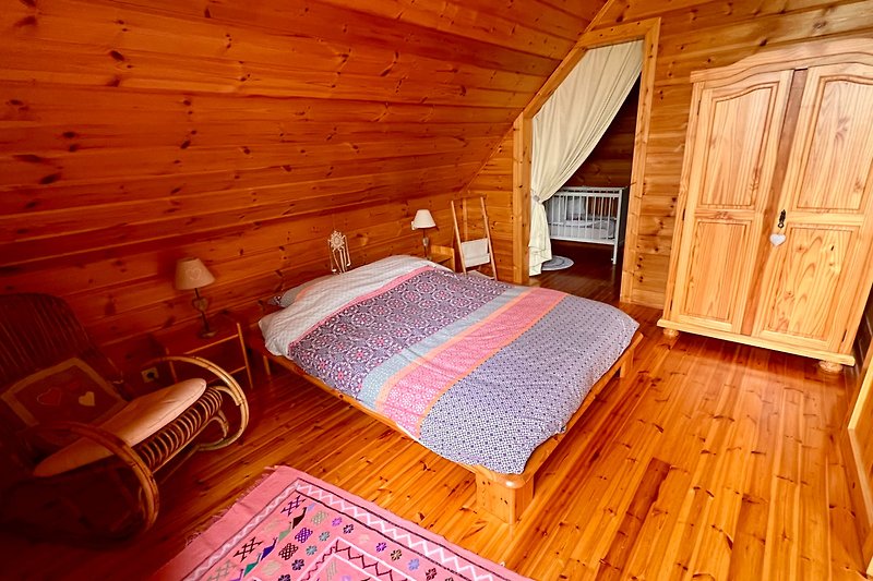 Schlafzimmer mit rustikalem Holzbett und Deckenbalken.