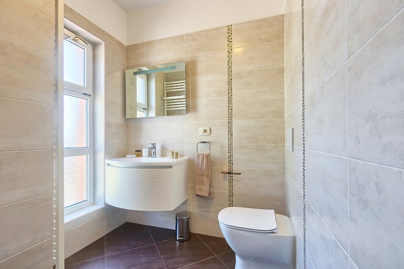 Prekrasna kupaonica s modernim namještajem i elegantnim zrcalom.