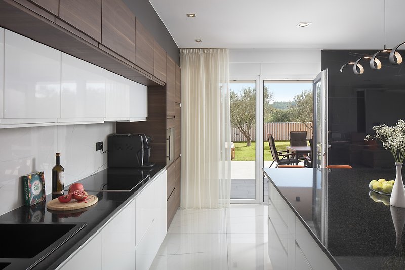 Moderan kuhinjski prostor s drvenim podom i staklenim prozorima.
