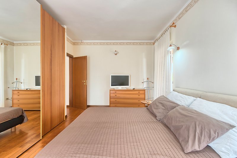 Prekrasno uređena spavaća soba s drvenim namještajem i udobnim krevetom.