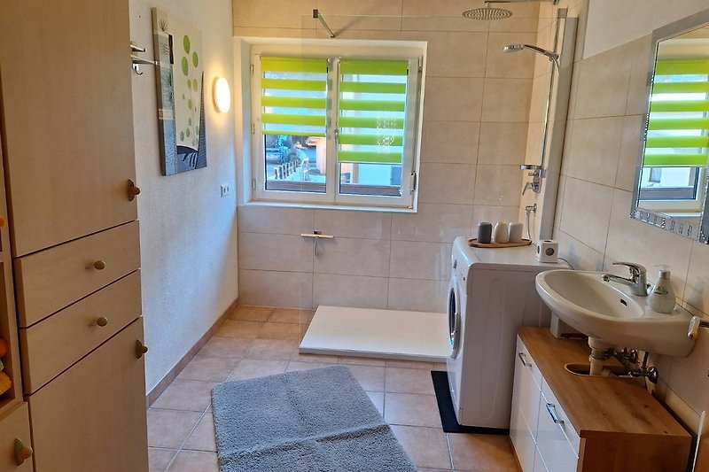Ein modernes Badezimmer mit Spiegel, Waschbecken und Badewanne.