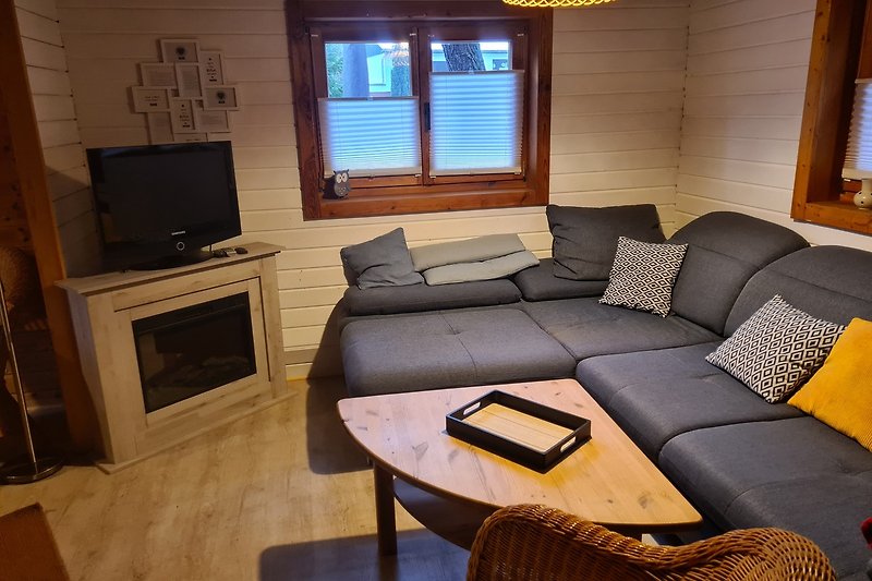 Gemütliches Wohnzimmer mit Holzmöbeln, Couch und Fernseher.