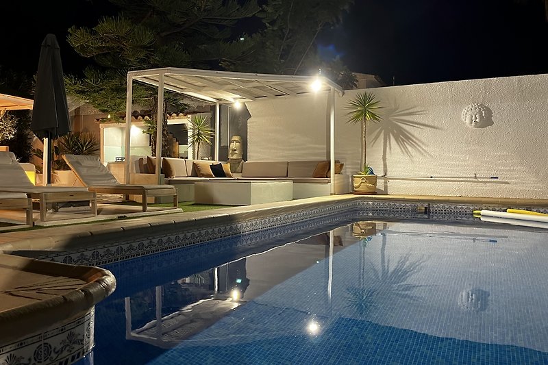 Prachtig zwembad met verlichting, omgeven door een weelderige tuin.