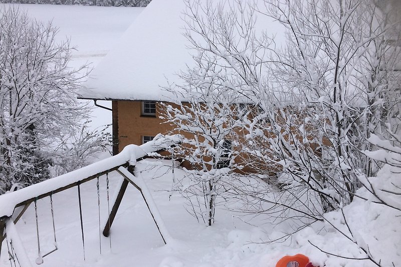 Winterliches Ferienhaus mit verschneiter Landschaft und gemütlichem Holzhaus.