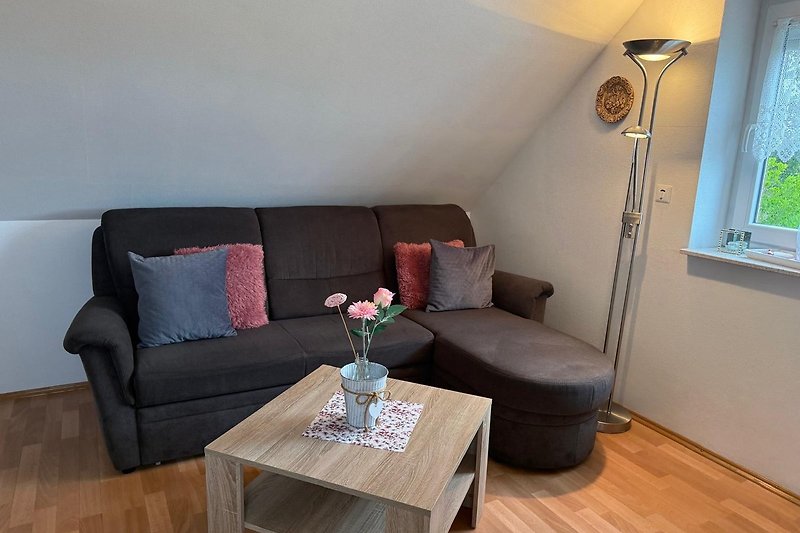 Wohnzimmer mit Couch, Holzmöbeln und großem Flachbildfernseher.