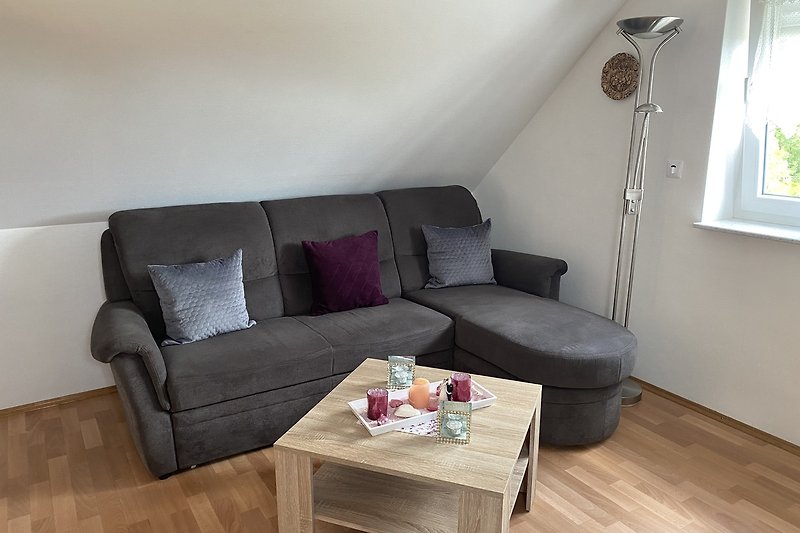 Gemütliches Wohnzimmer mit brauner Couch und Holzmöbeln. Entspannen Sie sich vor dem Fenster und genießen Sie den Komfort.