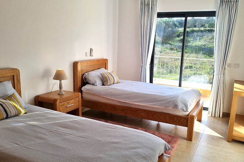 Gemütliches Schlafzimmer mit Holzbett und Schiebefenster mit direkter Terassenzugang