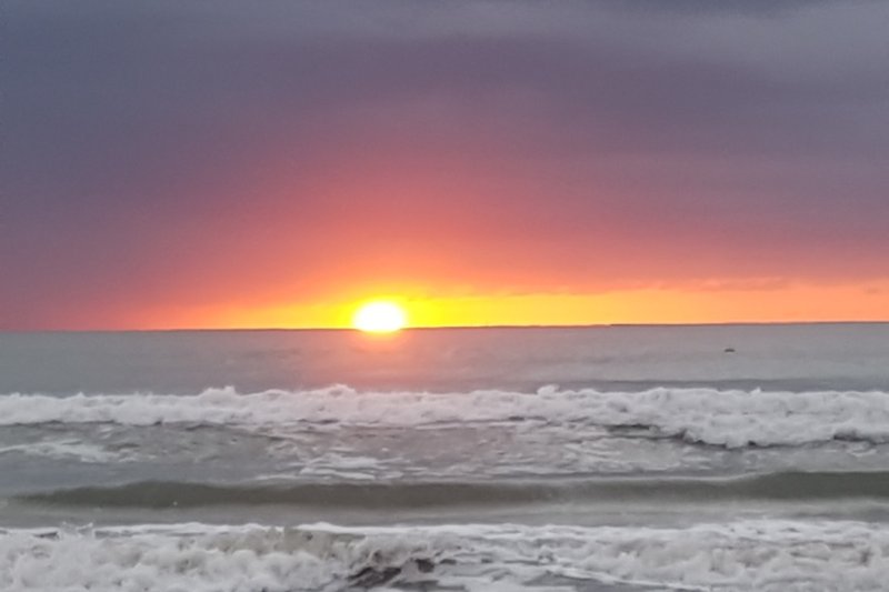 Ruhiger Sonnenuntergang am Meer mit rotem Himmel und ruhiger See.