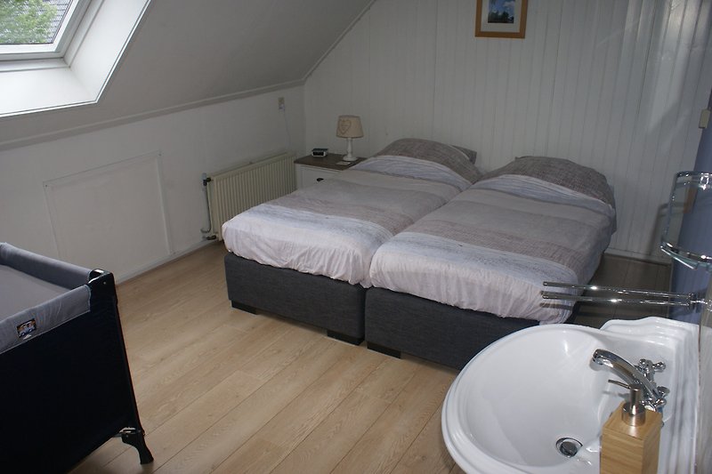 One of the upstairs twin bedrooms with washbasin, wardrobe, boxspring beds and here with cot