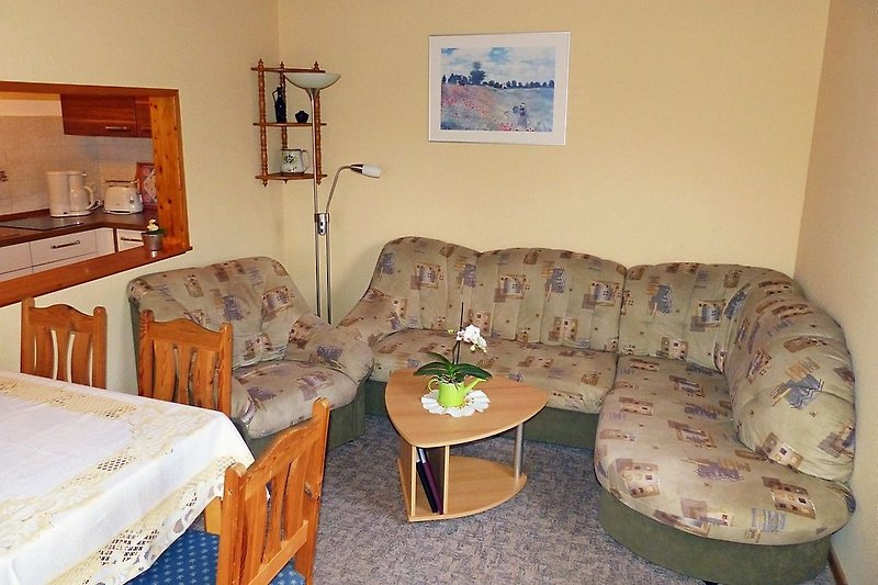Wohnzimmer mit Esstich, Sessel und Eck-Couch