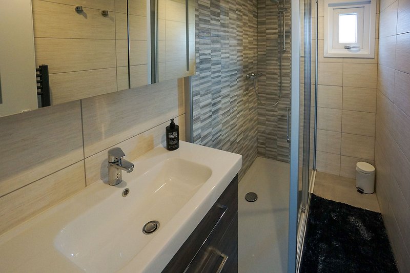 Modernes Badezimmer mit Spiegel, Waschbecken und Glasdusche.
