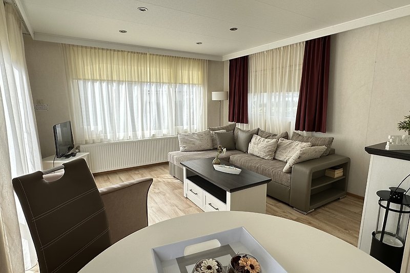 Wohnzimmer mit bequemer Couch, Tisch, Lampe und Vorhängen.