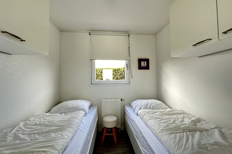 Schlafzimmer mit Holzbett, Bettwäsche und Fenster.