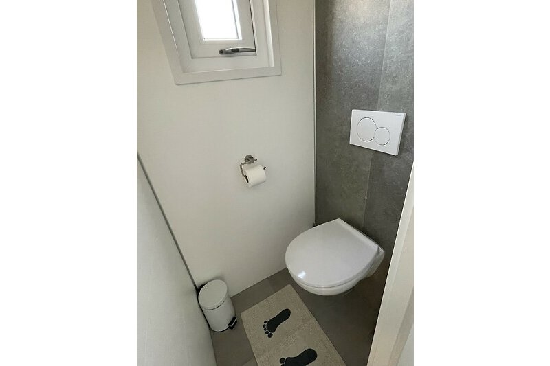 Toilette mit lila Wand, weißem Waschbecken und Toilettenpapierhalter.