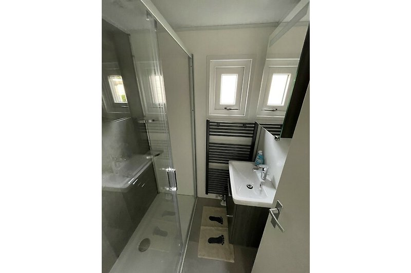 Ein stilvolles Badezimmer mit Holzboden, Spiegel und modernen Armaturen.